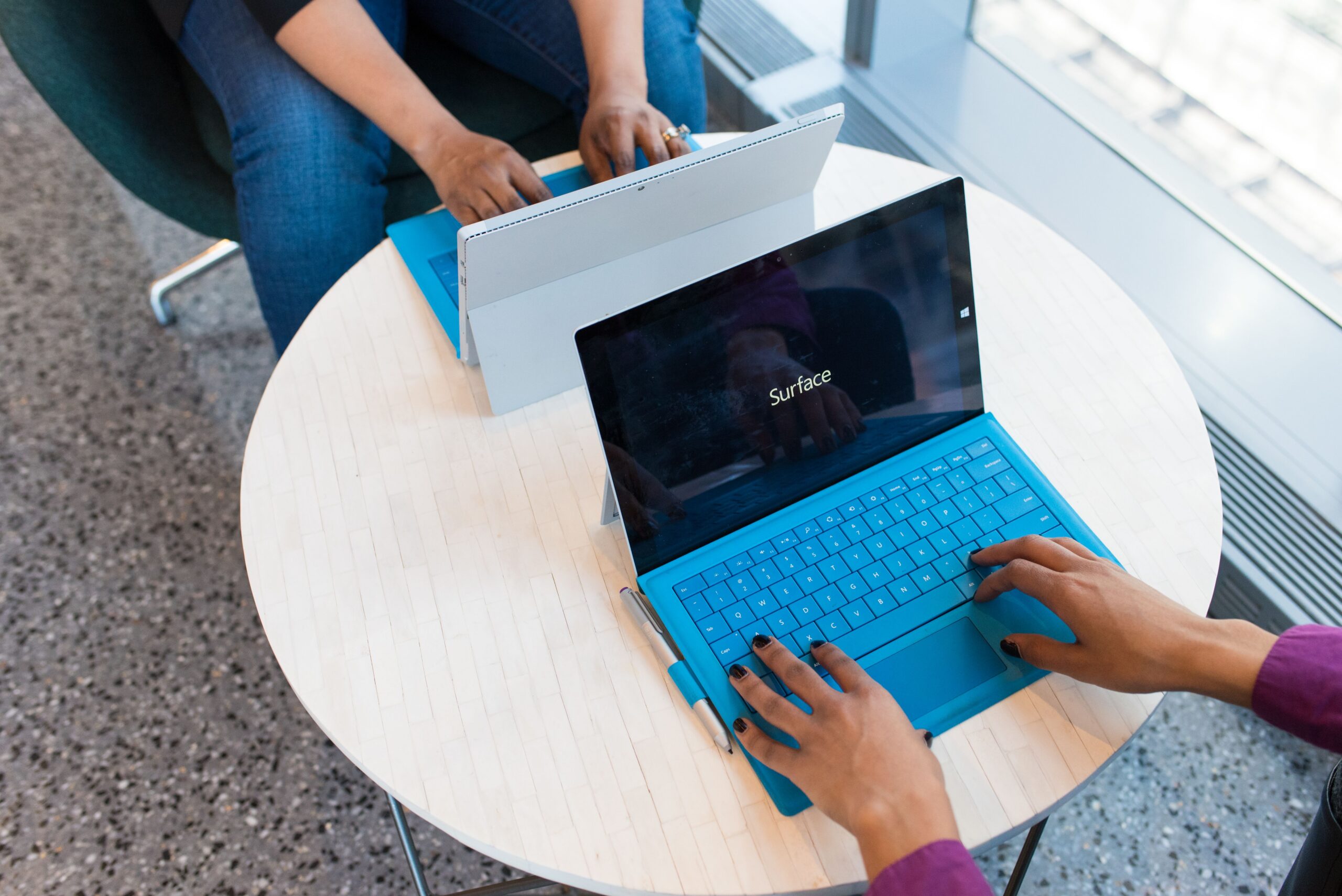 Two individuals working on laptops indoors, embodying remote work and technology.